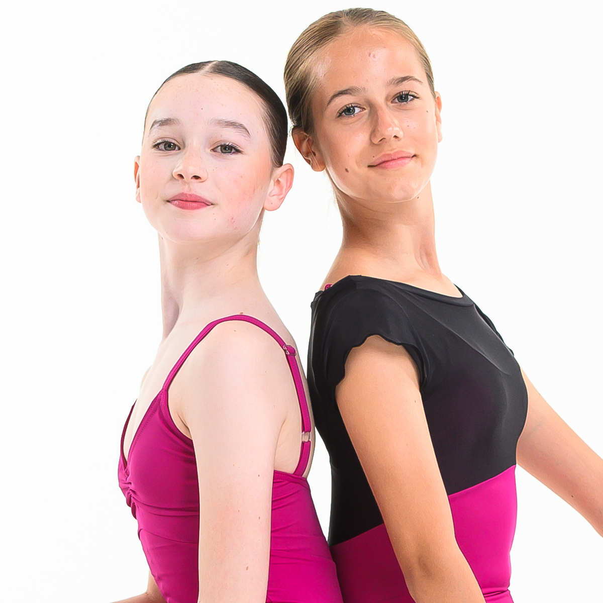 Two female teenage dancers posed back to back wearing pink ISTD leotards